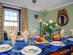 uma sala de jantar com uma mesa azul com pratos e flores em Trefrane House-qc1119 em Roch