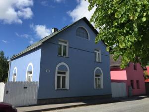 a blue building with white windows on a street at House in the Garden in Pärnu