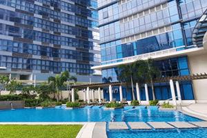 a swimming pool in front of a tall building at Cozy 1BR Apartment in Manila, BGC, with Balcony & Pool in Manila