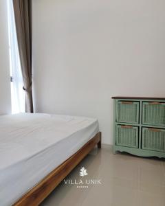 a bedroom with a bed and a dresser at Villa Unik Dau Malang in Malang