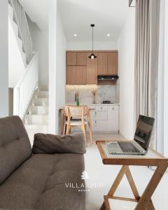 a living room with a couch and a table with a laptop at Villa Unik Dau Malang in Malang