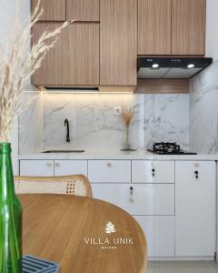 a kitchen with white cabinets and a wooden table at Villa Unik Dau Malang in Malang