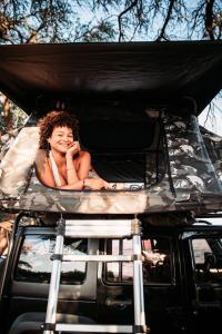 a woman laying in the bed of a car at Zazu Campers in Kahului