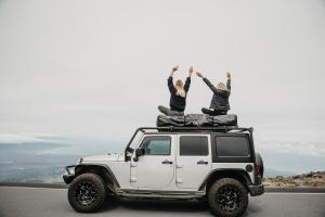 dos personas sentadas en el techo de un jeep blanco en Zazu Campers, en Kahului