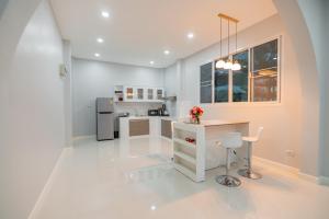 a white kitchen with a table and a refrigerator at In Love Chiangmai หลงรักเชียงใหม่ in Ban Tai