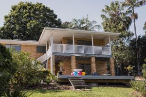 a house with a balcony and palm trees at Pet and family friendly- with its own lake and 3 mins from town! in Maleny