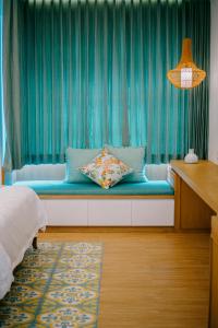 a bedroom with a bench with a blue curtain at Casa Amarta - Canggu in Canggu