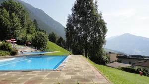 a swimming pool on a hill with mountains in the background at Ferienwohnung Leitner in Grins