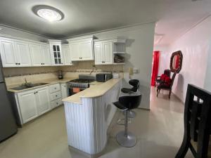 uma cozinha com armários brancos e bancos pretos em 5amazing Huge Nice Furnished Apt 2 Stay Longterm em Santo Domingo