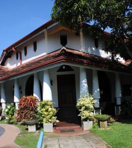 un bâtiment blanc avec des plantes en pot devant lui dans l'établissement Olideb Gedara, à Negombo