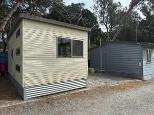 a small white building with a window next to a garage at Second Valley Caravan Park in Second Valley