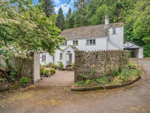 une maison blanche avec une clôture en pierre devant elle dans l'établissement The Carriage House, à Llanwenarth