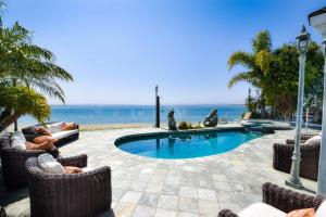 a swimming pool with chairs and the ocean in the background at Private Beach front 4bed 4bath pool and spa house in San Diego
