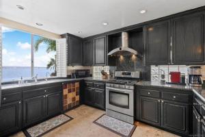 eine Küche mit schwarzen Schränken und Meerblick in der Unterkunft Private Beach front 4bed 4bath pool and spa house in San Diego