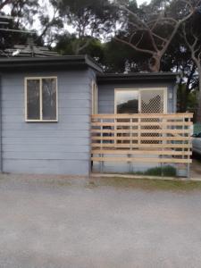 ein kleines Haus mit einem Holzzaun davor in der Unterkunft Second Valley Caravan Park in Second Valley