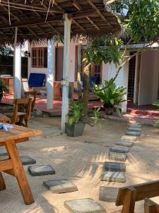 a patio with wooden tables and benches and a house at Avalon in Weligama