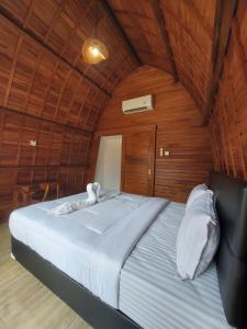 uma cama grande num quarto com paredes de madeira em Les Chalets Pecatu em Uluwatu