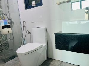 a white bathroom with a toilet and a sink at D Beep Beep Homestay Vivacity Homestay in Kuching
