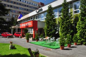 un hotel con mesa y sillas frente a un edificio en Tatra Hotel, en Poprad