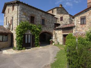 a large stone building with an archway and ivy at Agriturismo San Sano in Gaiole in Chianti