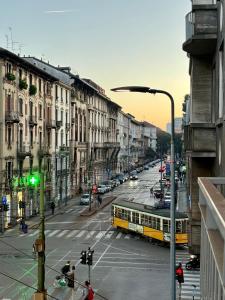 een gele bus die door een straat met gebouwen rijdt bij La casa di Albert - luxury living in Milaan