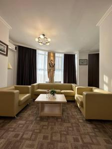 a living room with couches and a coffee table at Tanzharyk Hotel in Aktobe