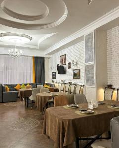 a dining room with tables and chairs and a couch at Tanzharyk Hotel in Aktobe