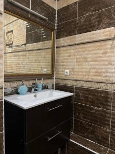 uma casa de banho com um lavatório e um espelho em Tanzharyk Hotel em Aqtöbe