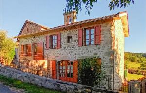 an old stone house with red windows and a tower at Gite Rural Le Couvent in Riom-ès-Montagnes