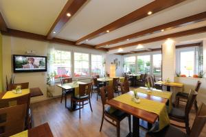 a restaurant with tables and chairs and a flat screen tv at Hotel Garni Schilling in Duisburg