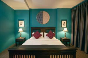 a bedroom with a bed with blue walls and two lamps at Caiyong in Khlong San