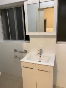 a bathroom with a white sink and a mirror at Gardens of Eden Sydney North in Sydney