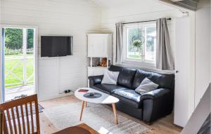sala de estar con sofá de cuero negro y mesa en Cozy Home In Henn With Kitchen en Henån