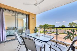 a dining room with a table and chairs and a balcony at Cute & Cosy Darwin Waterfront Apartment with Queen Bed in Darwin