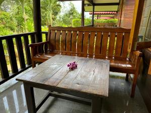 a wooden bench with a purple flower on a porch at Samed Garden Resort in Ko Samed