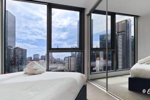 een slaapkamer met een bed en een groot raam bij Southbank 23F 1BR 4Guest City Skyline Pool & Gym in Melbourne