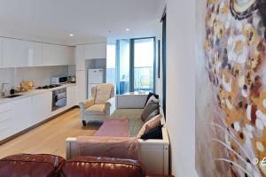een woonkamer met een bank en een keuken bij Southbank 23F 1BR 4Guest City Skyline Pool & Gym in Melbourne