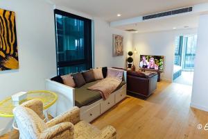een woonkamer met een bank en een tv bij Southbank 23F 1BR 4Guest City Skyline Pool & Gym in Melbourne