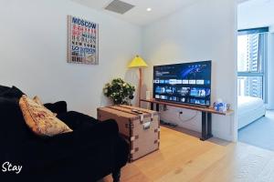 ein Wohnzimmer mit einem Sofa und einem Flachbild-TV in der Unterkunft Southbank 26F 1BR Sea-View City Skyline Pool & Gym in Melbourne