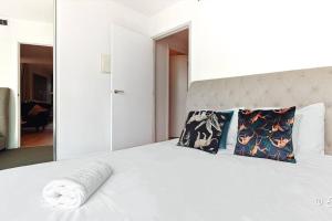 ein Schlafzimmer mit einem weißen Bett mit Kissen und einem Spiegel in der Unterkunft Southbank 26F 1BR Sea-View City Skyline Pool & Gym in Melbourne