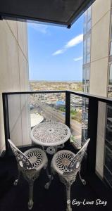 einen Balkon mit einem Tisch und Stühlen sowie einem Fenster in der Unterkunft Southbank 26F 1BR Sea-View City Skyline Pool & Gym in Melbourne