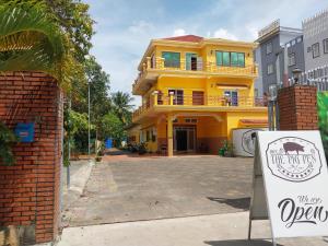 a yellow house with a sign in front of it at The Pig Pen Hostel & BBQ in Kampot