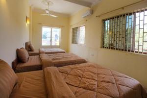 a bedroom with three beds and two windows at The Pig Pen Hostel & BBQ in Kampot