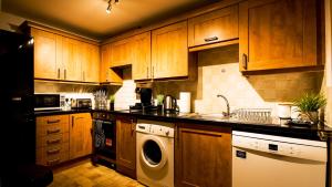 cocina con armarios de madera, lavadora y secadora en SOUTHAMPTON Central Apartments - Wise Stays en Southampton