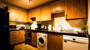 cocina con armarios de madera, lavadora y secadora en SOUTHAMPTON Central Apartments - Wise Stays, en Southampton