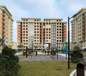 a park with a playground in front of a large building at Boulevard in Sumqayıt
