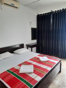 a bedroom with a bed with a red striped blanket at White Surfing Beach Resort in Unawatuna
