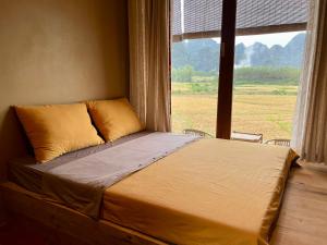 Bett in einem Zimmer mit einem großen Fenster in der Unterkunft Mai's House Hữu Lũng in Làng Ben