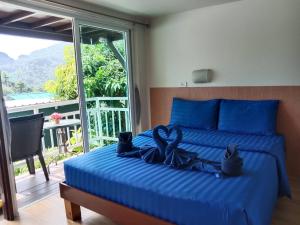 - une chambre avec un lit doté de draps bleus et une fenêtre dans l'établissement Blue View House Phi Phi, sur les Îles Phi Phi