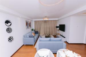 a living room with a blue couch and a tv at Ruaka Radiance 2-Bed Escape in Ruaka